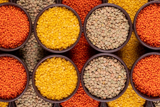 Yellow, green and red lentils in a brown bowls close-up