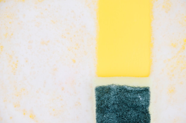 Free photo yellow and green sponges on white soap sud