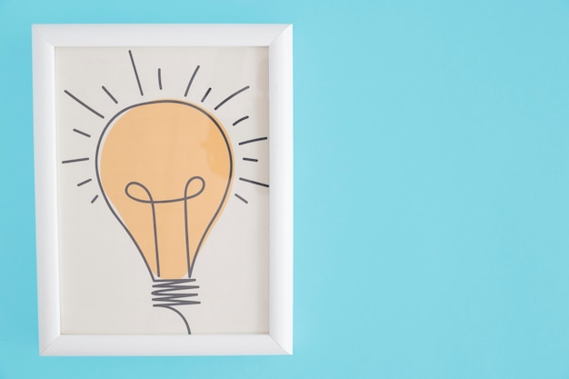 Free photo yellow hand drawn light bulb white frame over blue background