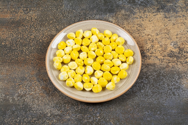 Free photo yellow hard candies on ceramic plate.