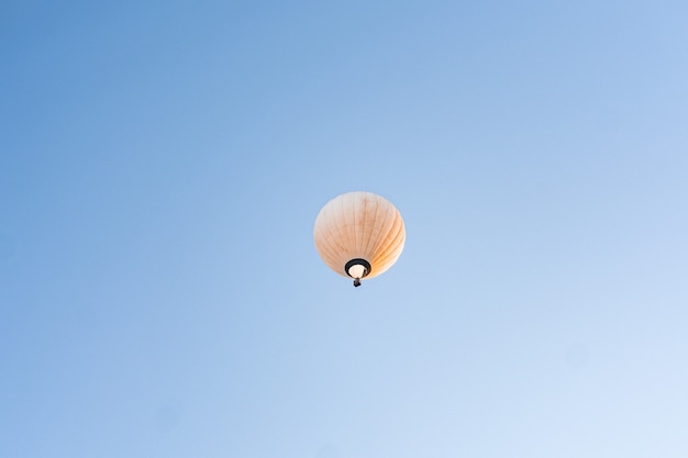 Yellow hot air balloon flying in clear blue sky