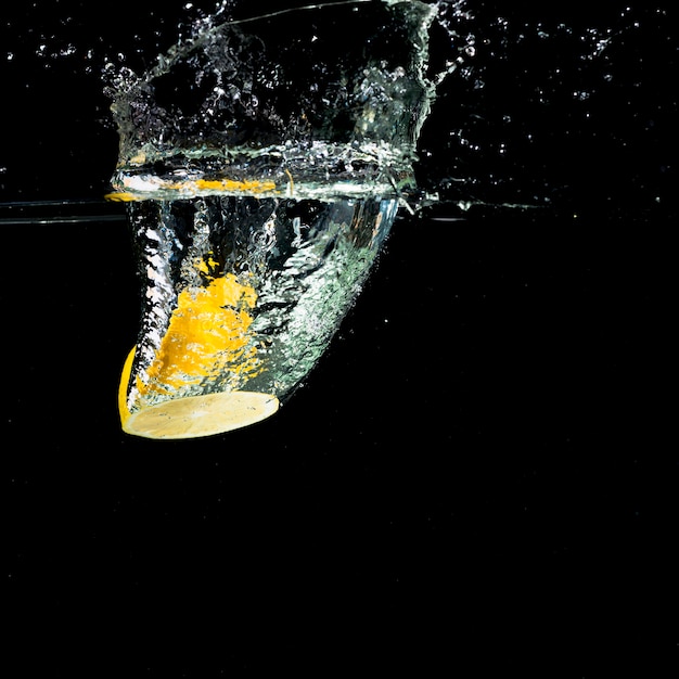 Limone giallo che cade nella spruzzata dell'acqua