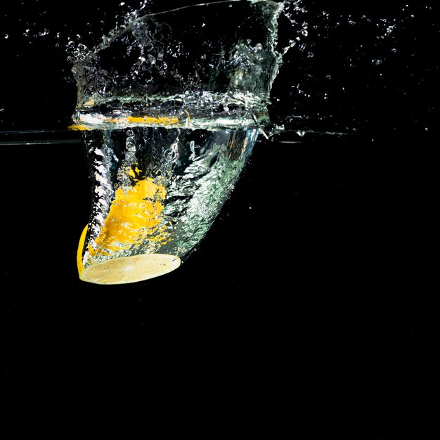 Yellow lemon falling into water splash