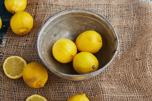 Yellow lemons in a metallic bowl. 