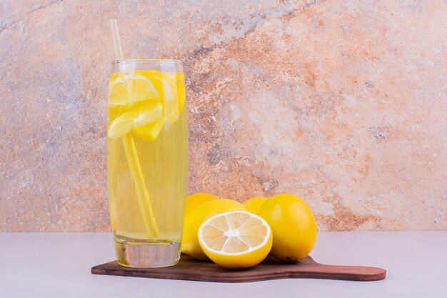 Желтые лимоны со стаканом лимонада.