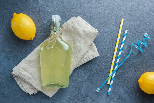Бесплатное фото Желтые лимоны с лимонным соком на белой тканевой ткани и плоской соломке лежат на белой поверхности