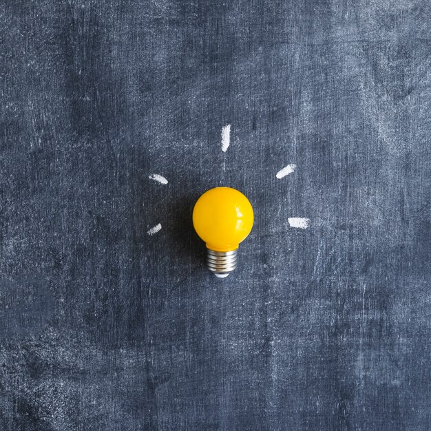 Yellow light bulb on chalkboard