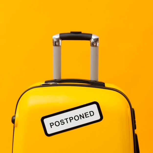 Yellow luggage with postponed sign