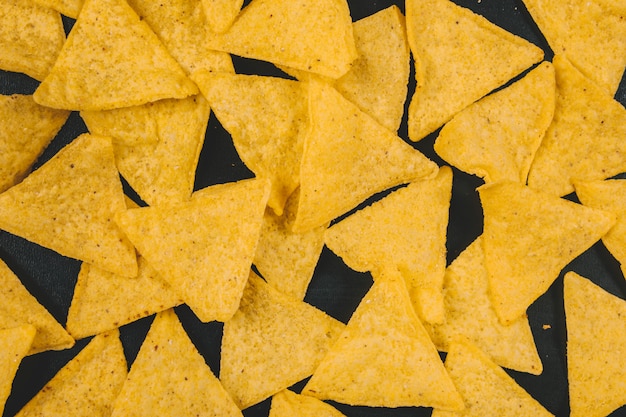 Yellow mexican nachos chips over black background