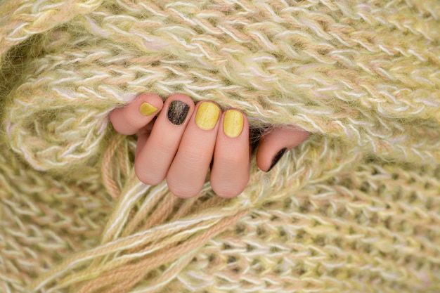노란 손톱 디자인. 반짝이 매니큐어와 잘 손질 된 여성 손입니다.