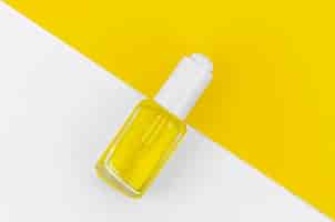Free photo yellow nail polish on white and yellow background