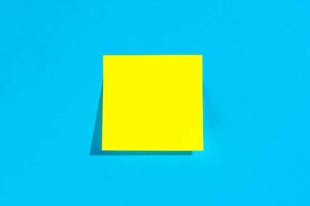 Yellow note with empty place for text on a blue background flat lay