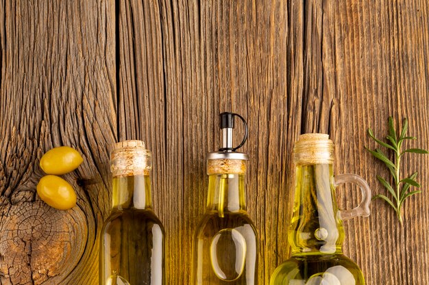 Yellow olives and oil bottles on wooden background