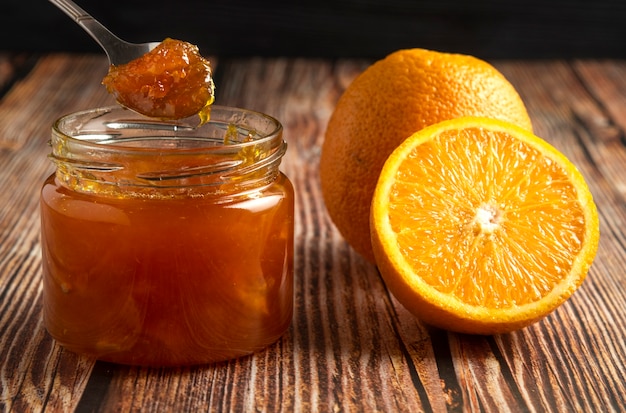 Yellow oranges with a jar of confiture.