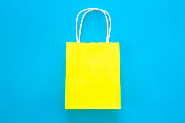 Бесплатное фото Желтый бумажный пакет на синем фоне, вид сверху