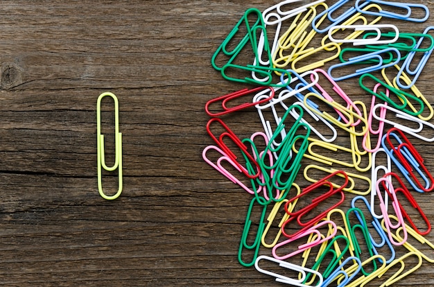 Yellow paper clip separated from group of colorful ones