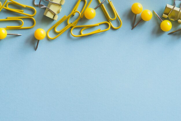 Yellow paper clips push-pins and binder clips