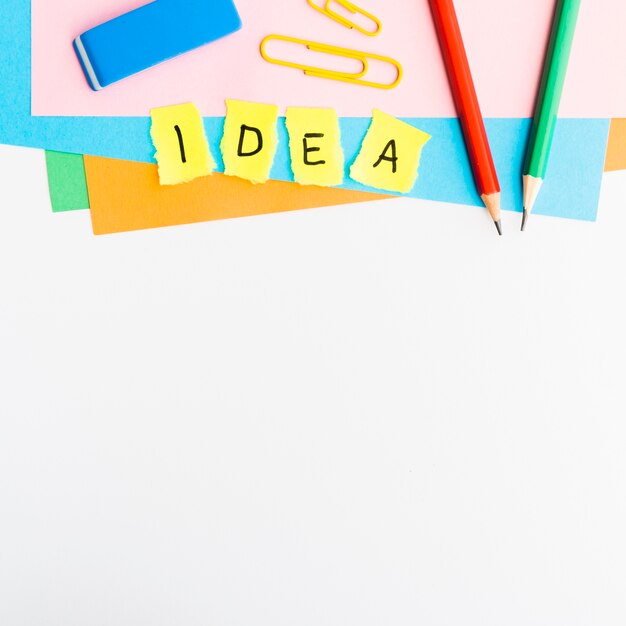 yellow paper pieces with idea text with school supplies isolated on white background