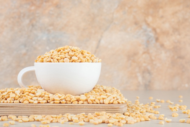 Yellow pea beans in a ceramic cup or bowl on concrete.