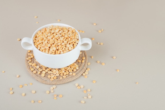 Yellow pea beans in a ceramic cup on concrete.