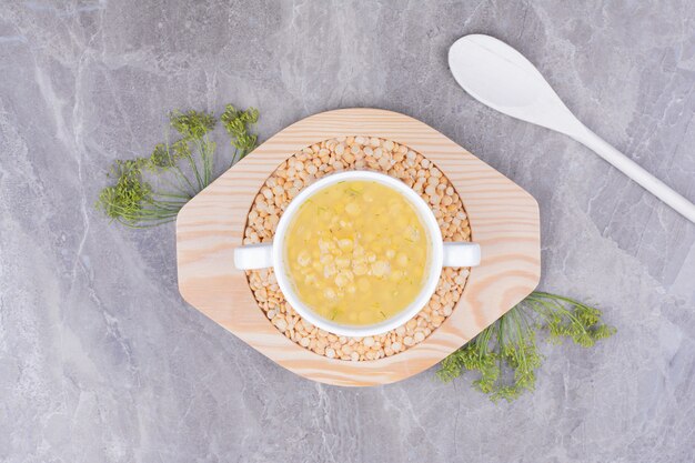 木の板の白いプレートに黄色いエンドウ豆のスープ