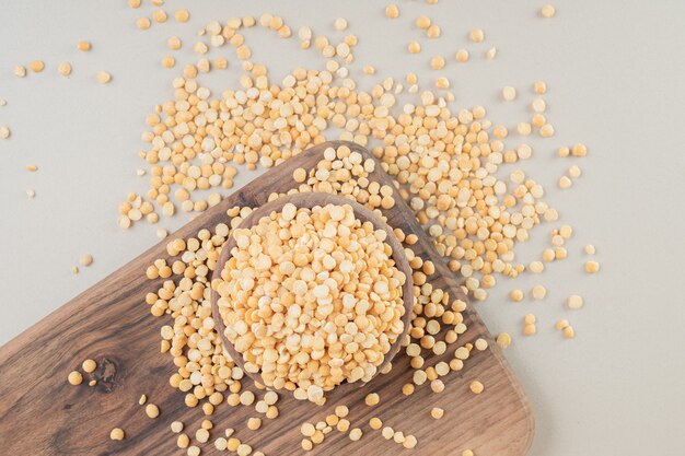 Yellow pea beans in a wooden cup on concrete.