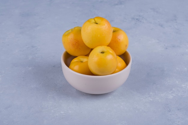 Yellow peaches in a white ceramic bowl