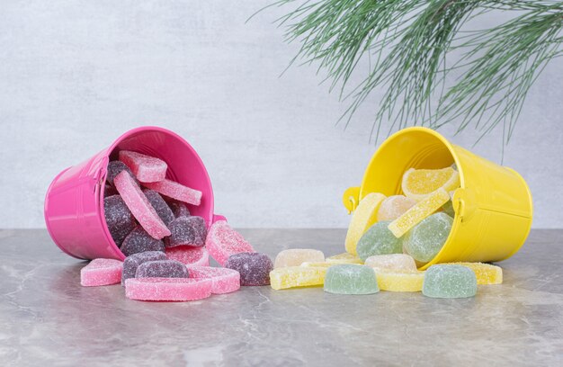 Yellow and pink buckets with sugar marmalade on marble background.