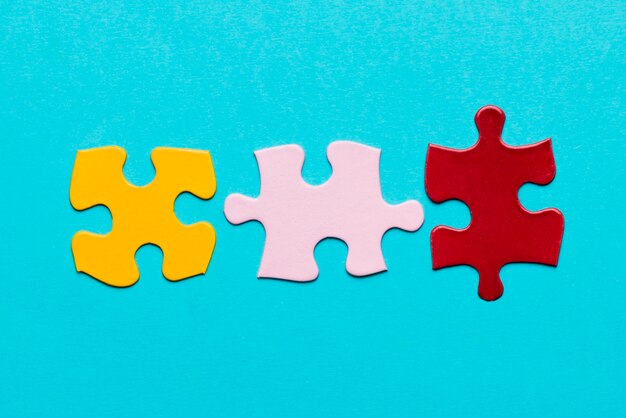 Yellow; pink and red jigsaw puzzle piece on blue textured background