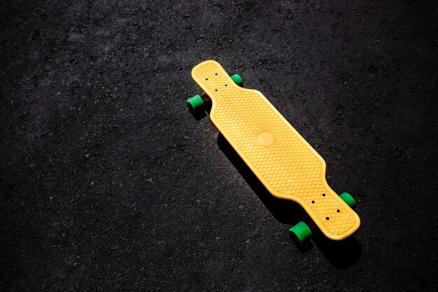 Yellow plastic longboard on the asphalt surface.