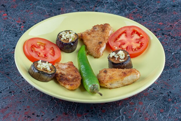 An yellow plate of chicken nuggets with vegetables .