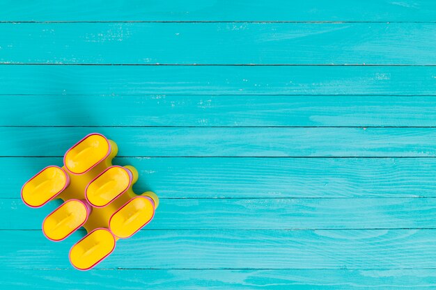 Yellow popsicle frost shape on a wooden surface