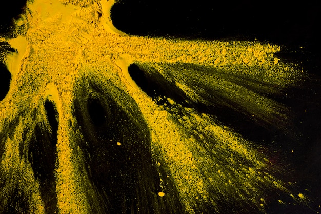 Yellow powder color exploding on black backdrop