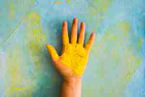 Free photo yellow powder on person's palm against painted messy wall with color