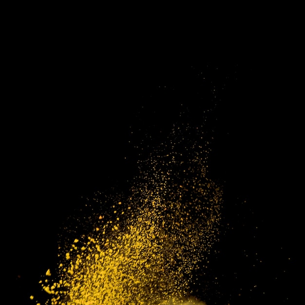 黄色の粉が黒の背景にこぼれた