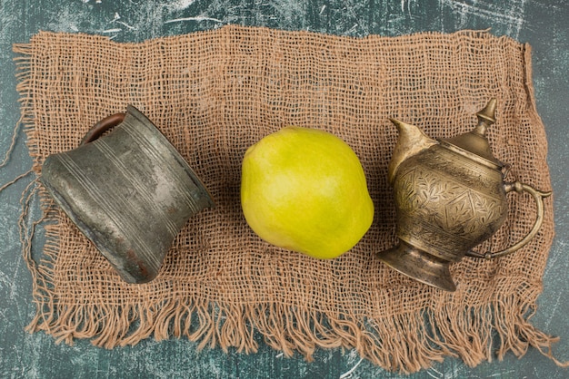 Yellow quince with ancient cups on burlap cloth