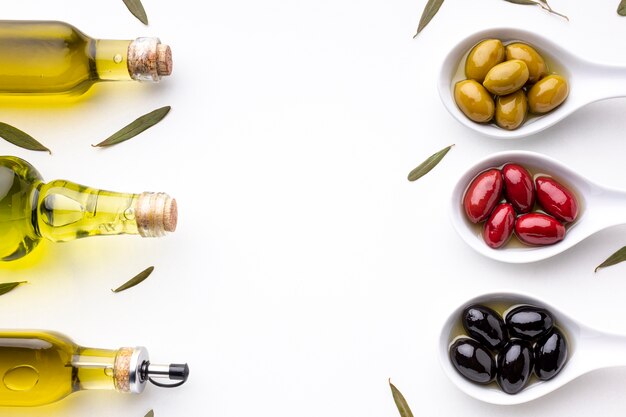 Желтые красные черные маслины в ложках с листьями и масляными бутылками