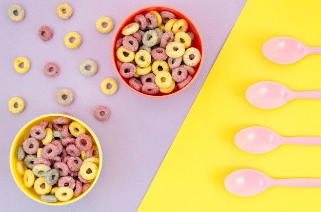 Yellow and red bowls of cereals and spoons