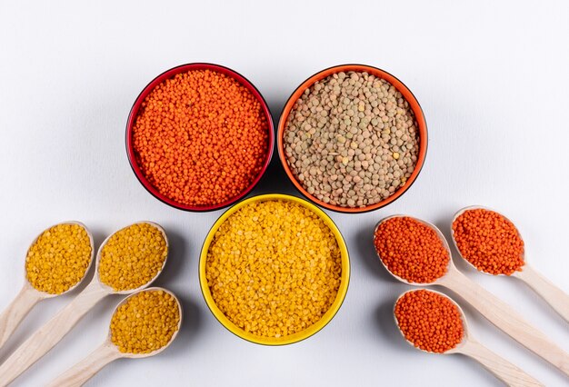 Yellow and red lentils in a wooden spoons and different colored bowls