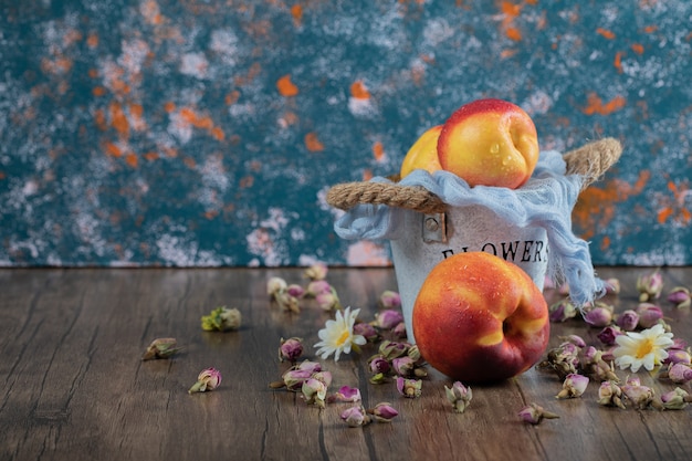 Yellow red peaches out of a blue metallic bucket. 