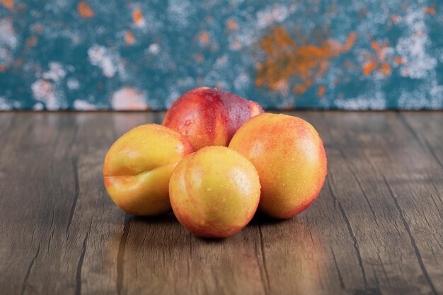 Free photo yellow and red peaches on wooden table.