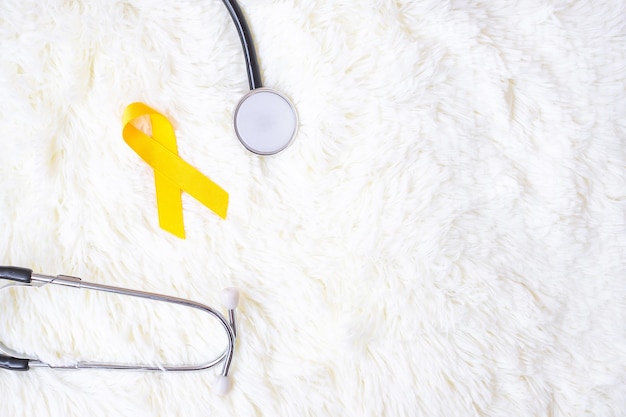 사람들의 생활과 질병을 지원하기 위해 흰색 바탕에 노란색 리본과 청진기. 9월 자살 예방의 날, 아동 암 인식의 달 및 세계 암의 날 개념