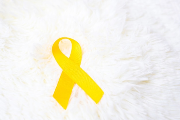 生きている​人々​と​病気​を​サポートする​ため​の​白い​背景​の​上​の​黄色い​リボン​。 9​月​の​自殺​予防デー​、​小児​がん​啓発​月間​、​世界​対がんデー​の​コンセプト
