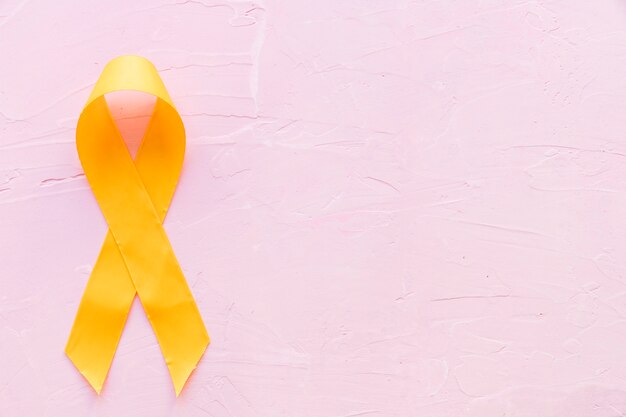 ピンクの背景に肉腫骨癌のための黄色のリボン象徴的な色