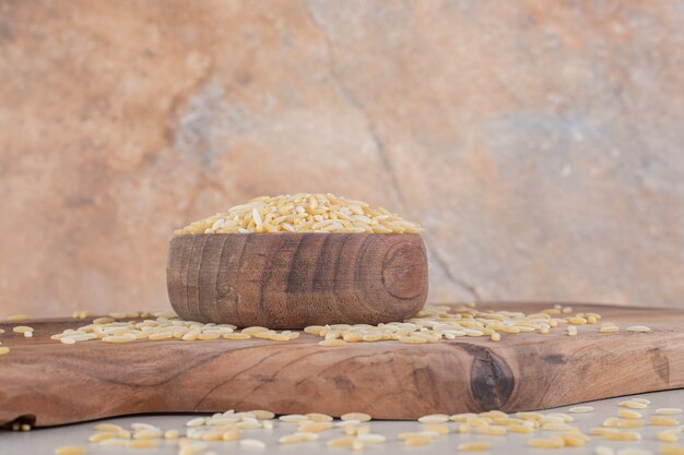 Yellow rice grains in a rustic wooden cup.