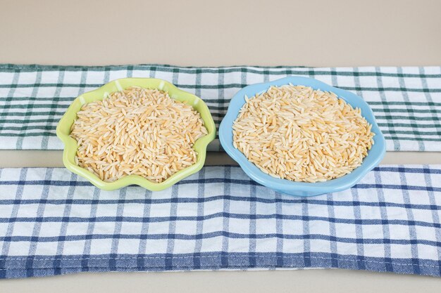 Yellow rice seeds in a ceramic cup on concrete.