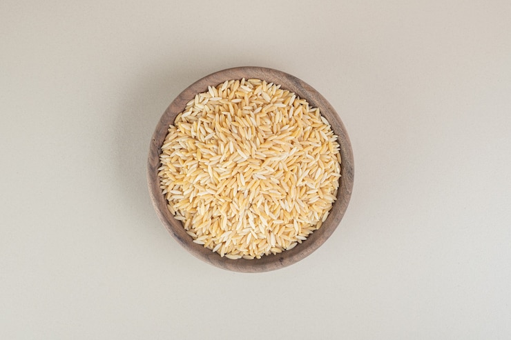 Free Photo yellow rice seeds in a wooden cup on concrete.