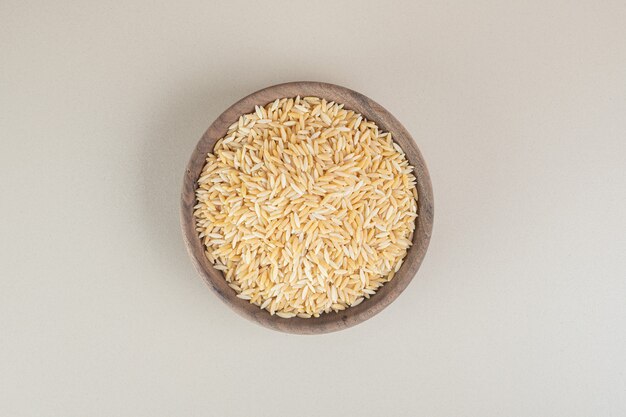 Семена желтого риса в деревянной чашке на бетоне.