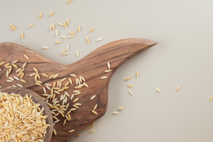 Free Photo yellow rice seeds in a wooden rustic cup on concrete.