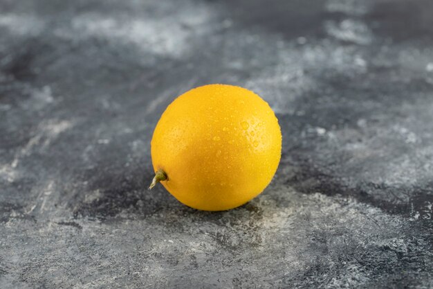 An yellow ripe lemon on a marble surface. 